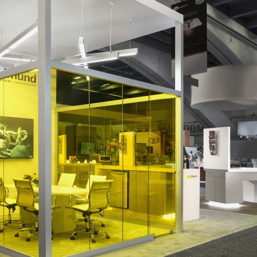 Edmund trade show booth, showing an office cubicle behind yellow glass