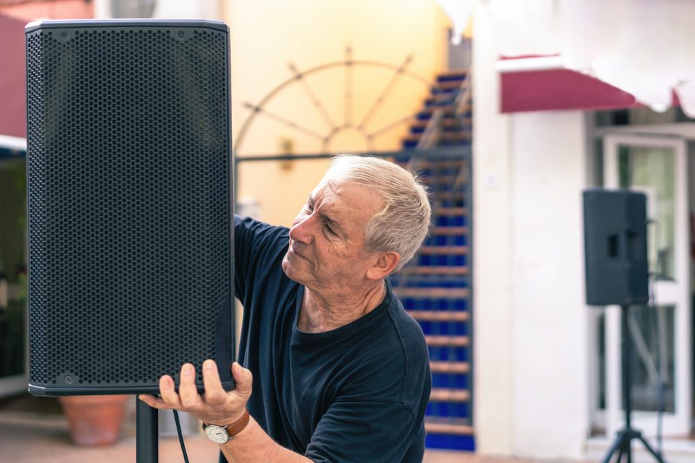 A trade show services provider sets up speakers for an exhibit.