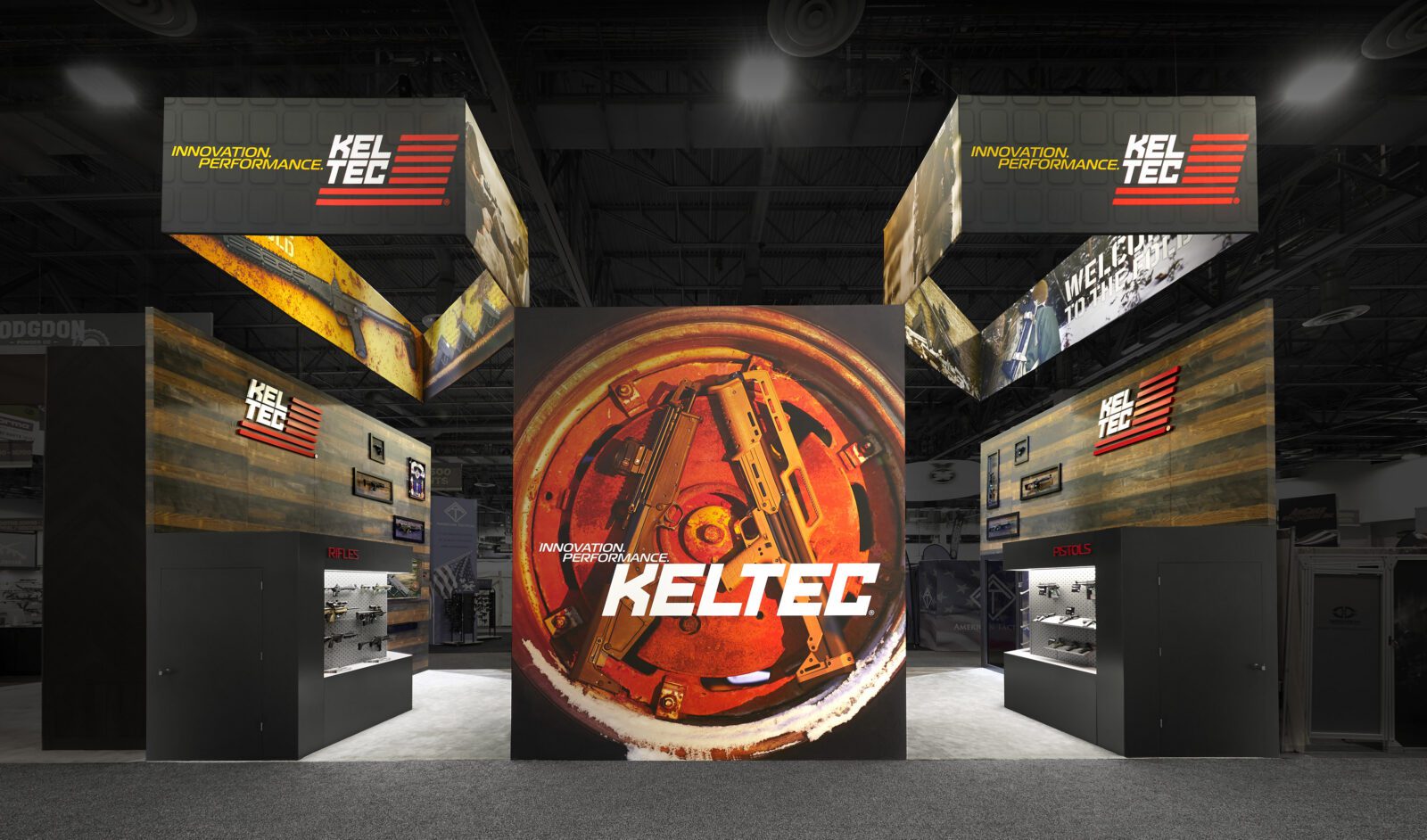 Trade show booth featuring KelTec branding, large circular gun part graphic, display cases with firearms, and hanging banners with the slogan "Innovation. Performance.