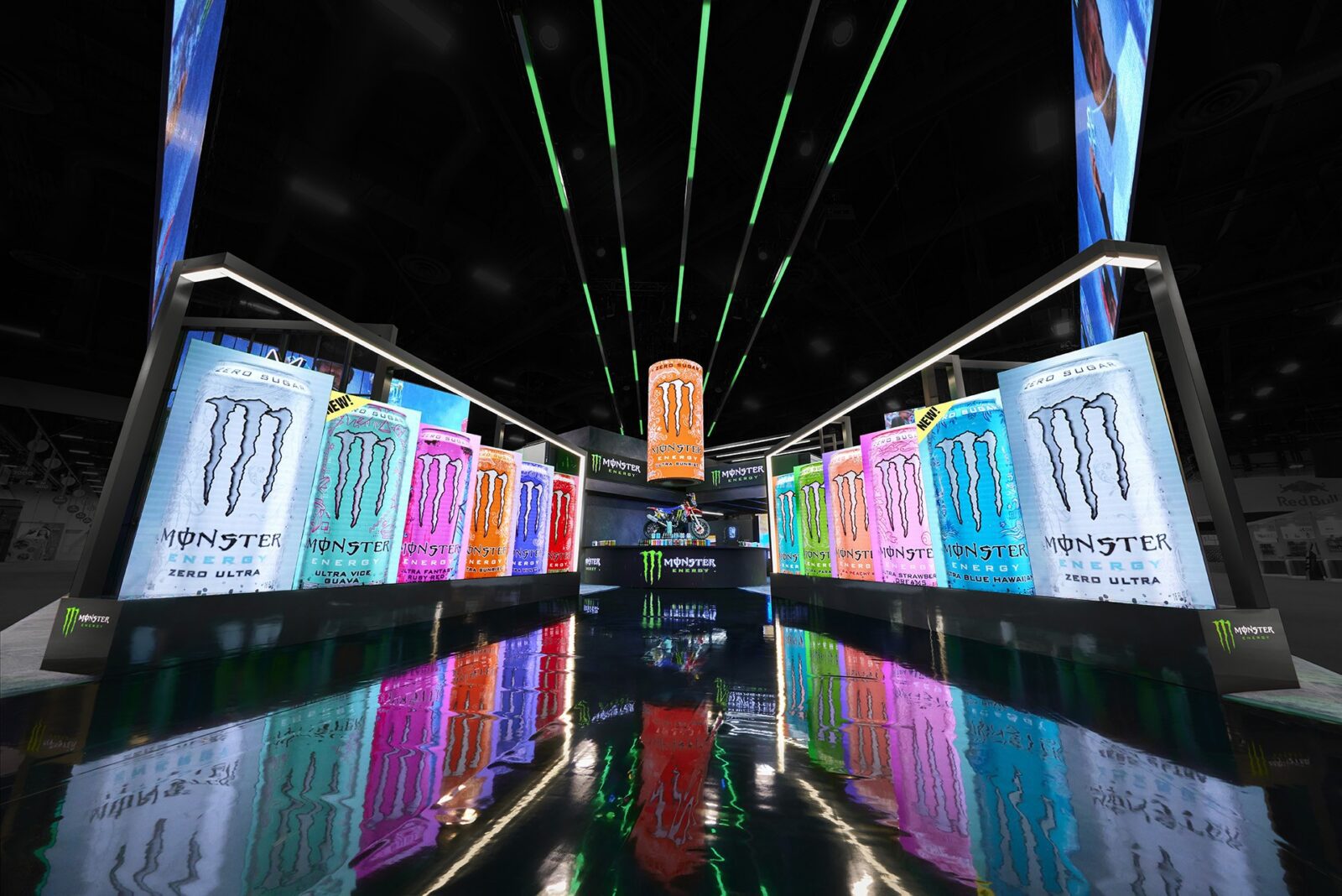 A display of Monster Energy drinks in various colors stands under bright lights, featuring large cans and vibrant reflections on the shiny floor—a striking example of innovative trade show design.